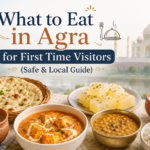 Traditional food in Agra featuring naan, paneer curry, dal, sweets, tea, and local dishes with the Taj Mahal in the background
