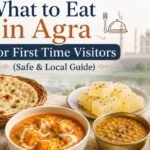 Traditional food in Agra featuring naan, paneer curry, dal, sweets, tea, and local dishes with the Taj Mahal in the background